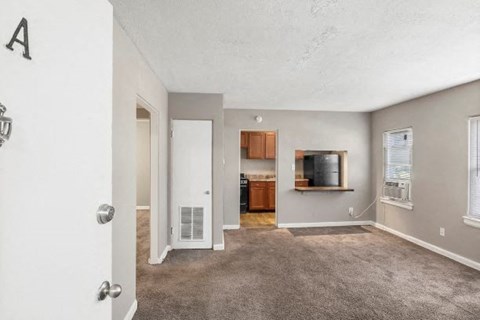 an empty living room with a tv and a kitchen