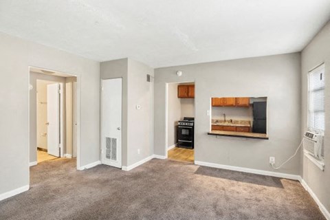 an empty living room with a fireplace and a kitchen