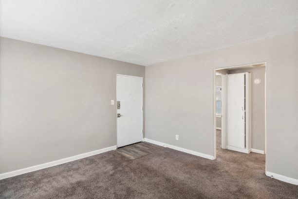 an empty living room with a door to a bedroom