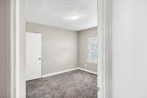 an empty room with a white door and a window