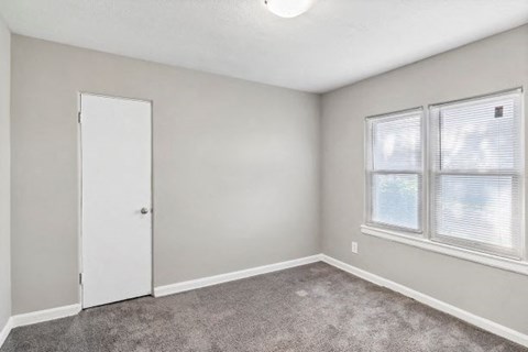 an empty room with a door and two windows