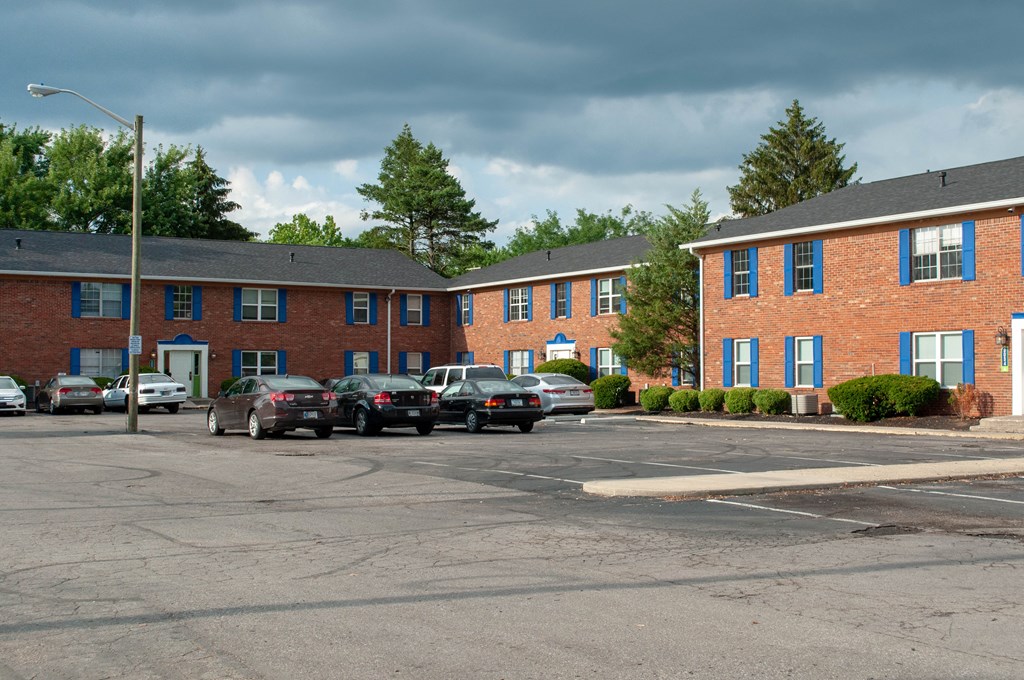 an empty parking lot in front of a brick apartment building