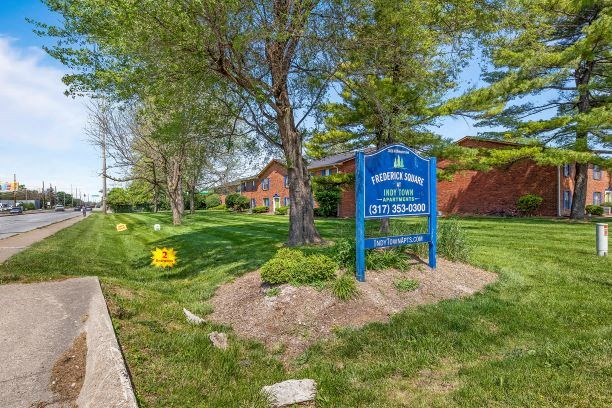 a blue sign in the grass in front of a house