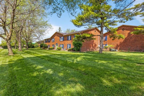 a large brick house with grass and trees