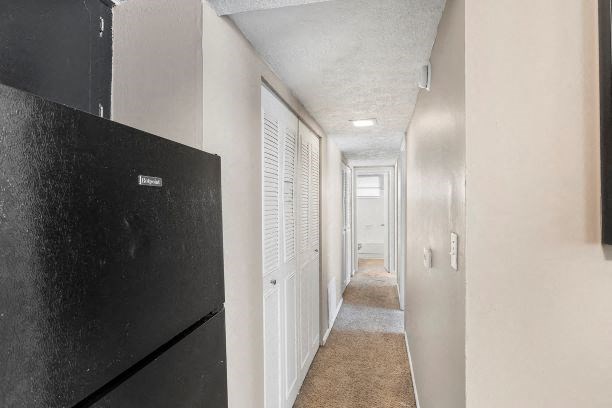 a hallway with a black refrigerator and white walls