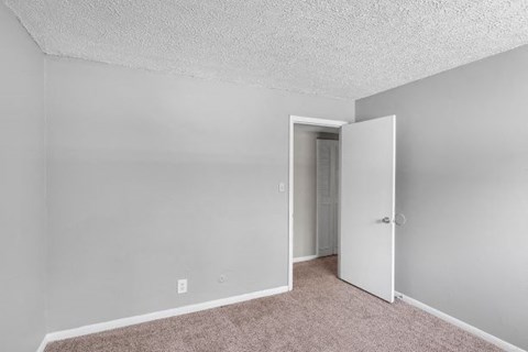 an empty bedroom with a door to a closet