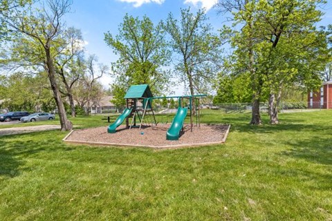 a playground with a green swing set in a park