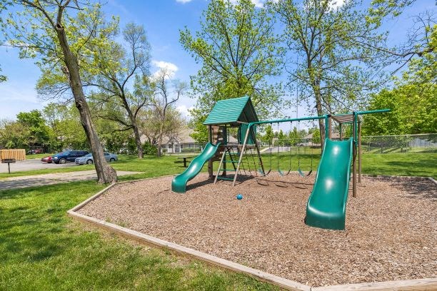 a playground with a slide and swings in a park