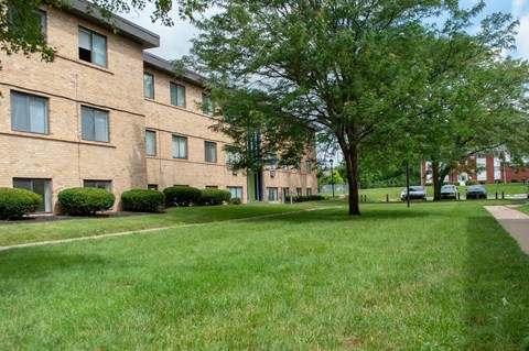 our apartments are located in a large brick building with green grass and trees