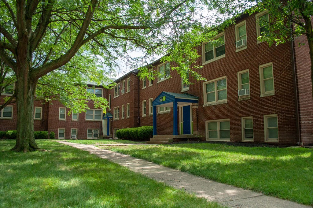 a sidewalk in front of a red brick apartment building