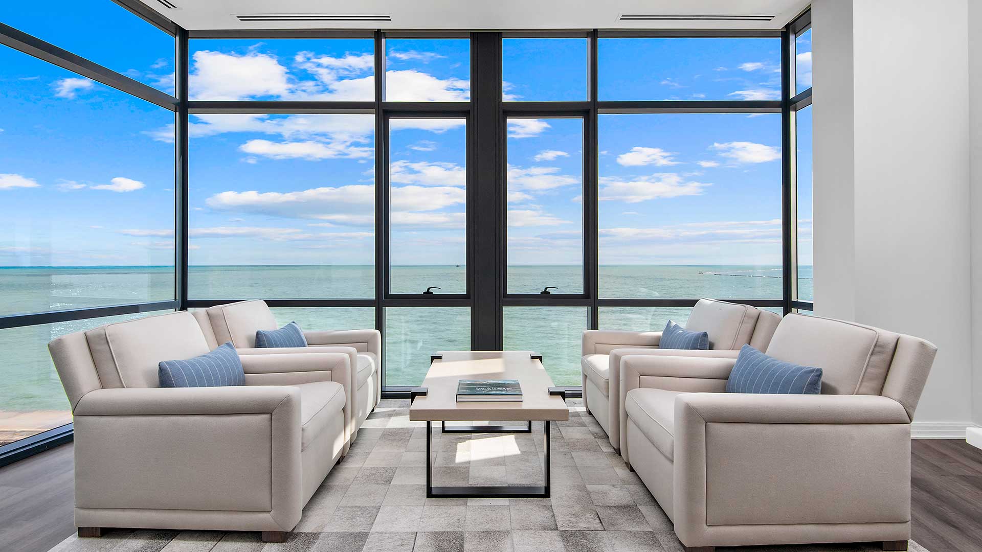 A living room set sits before floor-to-ceiling windows. Lake Michigan is seen outside.