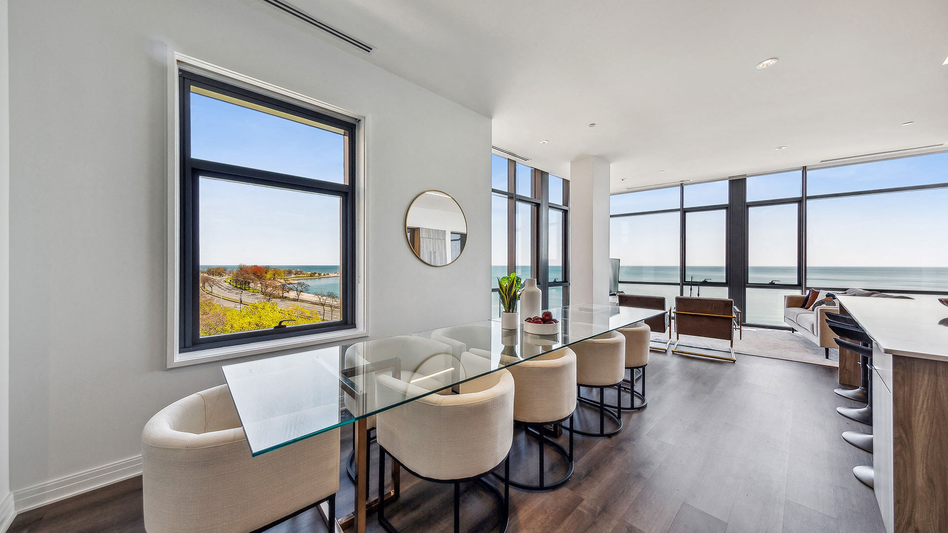 a dining room with a glass table and chairs and a view of the ocean