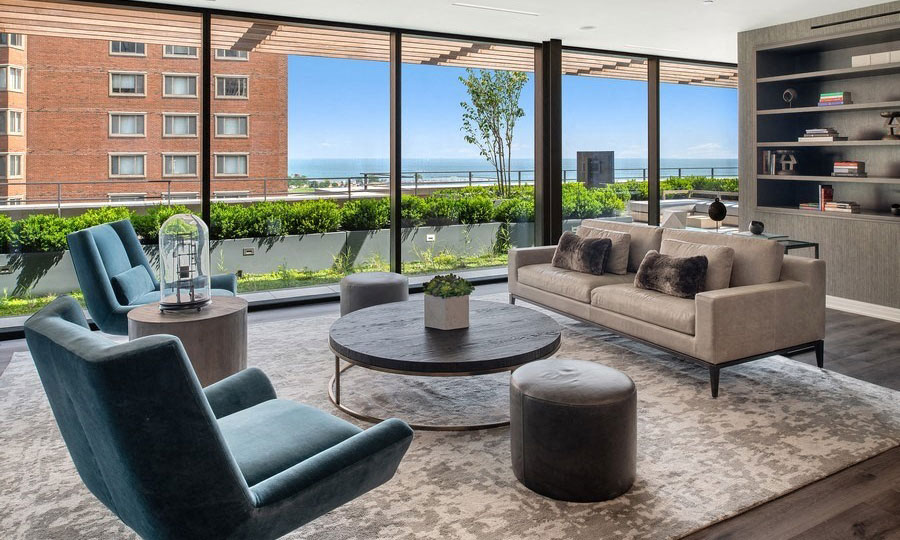 Club furniture around a round coffee table. The sky terrace can be seen outside with Lake Michigan in the background.