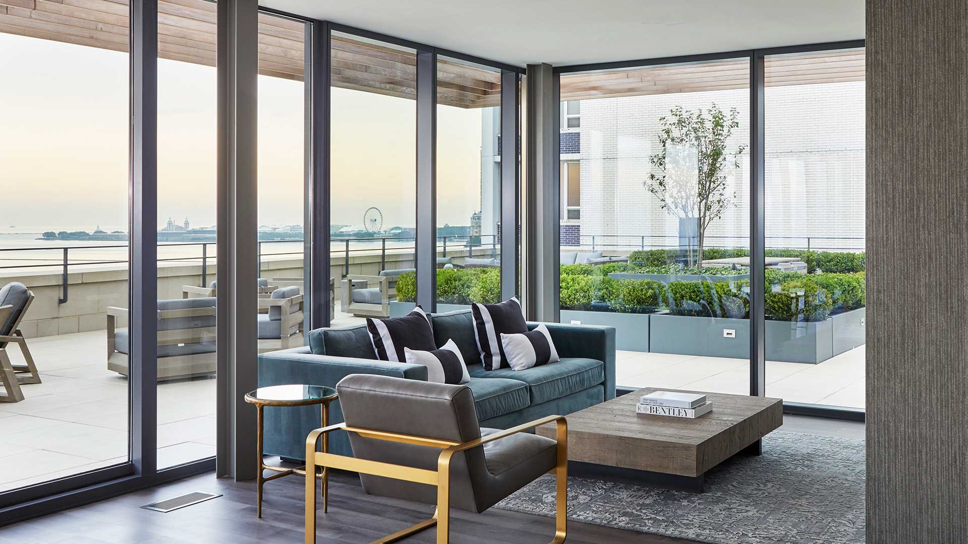 Club furniture and a coffee table site before a large television in the rooftop club at 61 Banks Street. The sky terrace can be seen outside the windows.