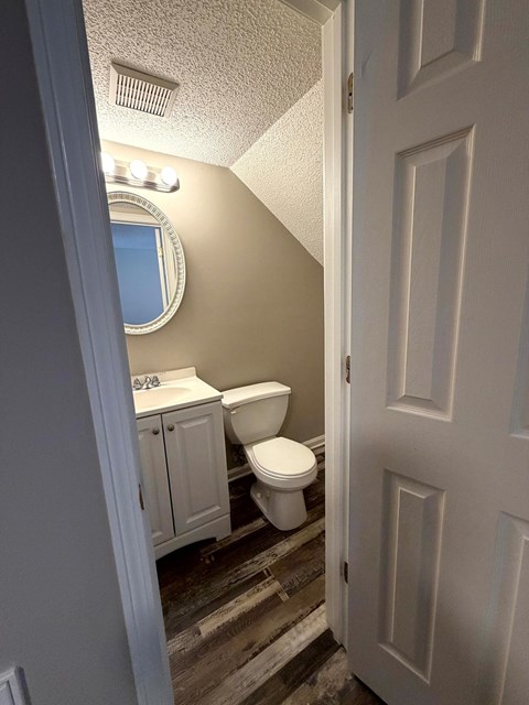 A bathroom with a toilet, sink, and mirror.