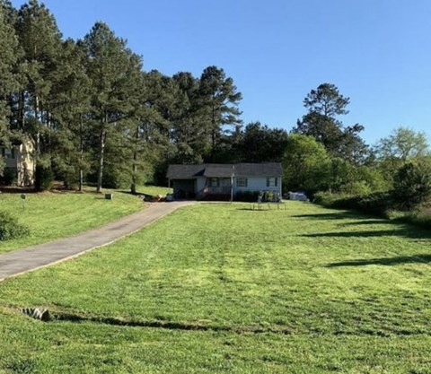 a house in the middle of a field next to a road
