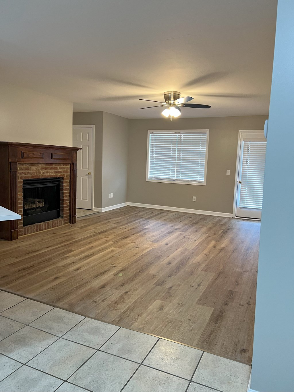 an empty living room with a fireplace and a ceiling fan