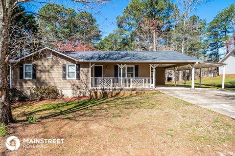 a small brown house with a porch and a lawn