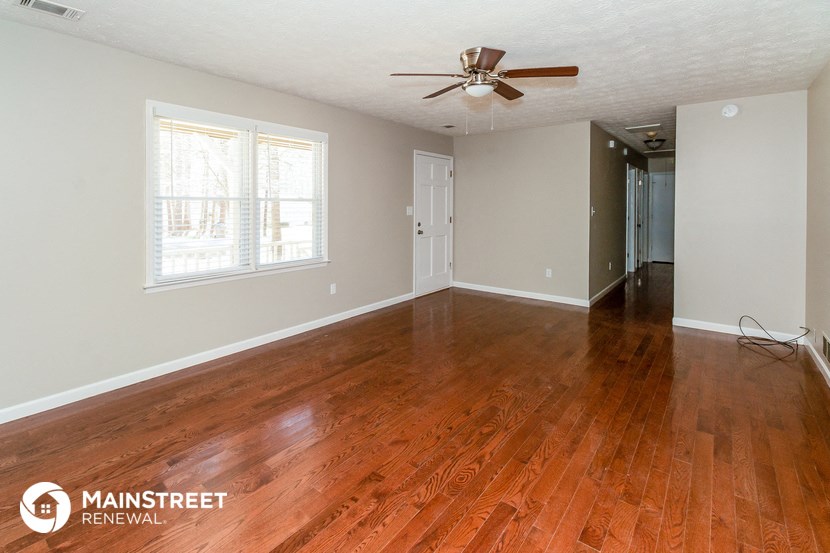 the living room of a home with wood floors and a ceiling fan