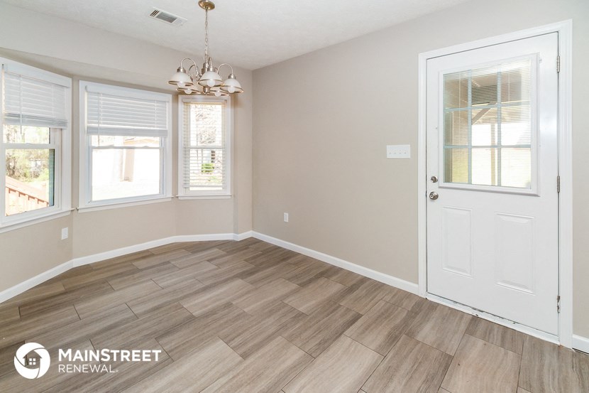 the living room of a home with a wooden floor and a white door