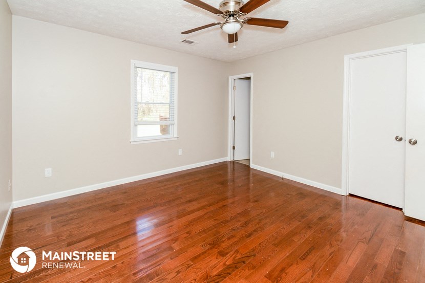 the living room with wood floors and a ceiling fan