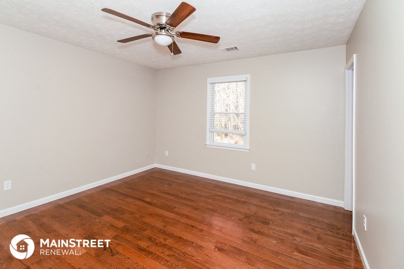 the living room of a home with wood floors and a ceiling fan