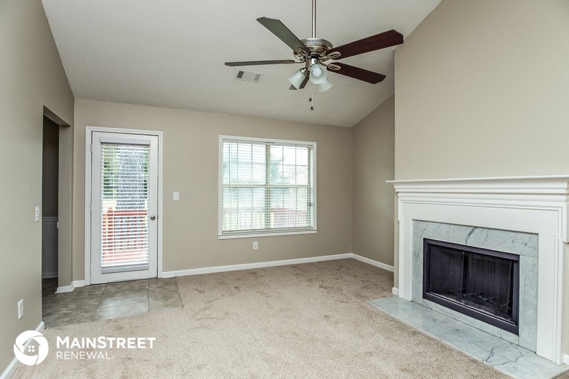 a living room with a fireplace and a ceiling fan