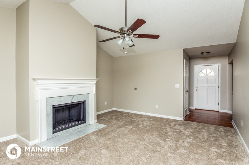 a living room with a fireplace and a ceiling fan