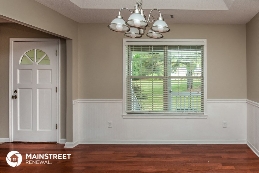 an empty room with a white door and a window with blinds