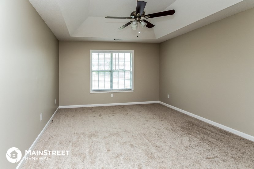 the master bedroom has a carpeted floor and a ceiling fan