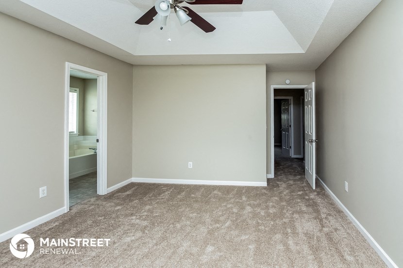 the master bedroom has a carpeted floor and a ceiling fan