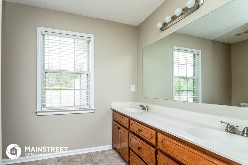 the master bathroom has two sinks and a large mirror
