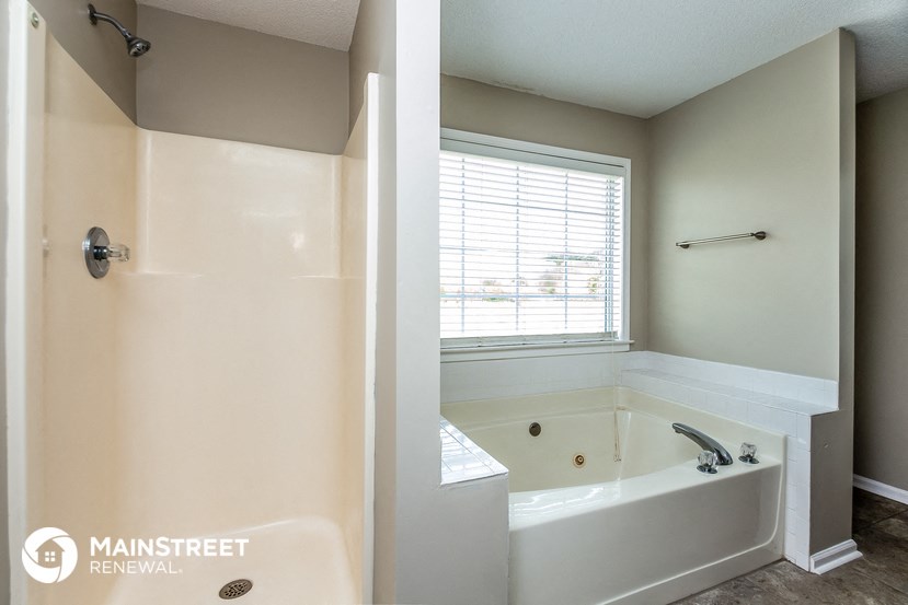 the master bathroom has a large tub and a window