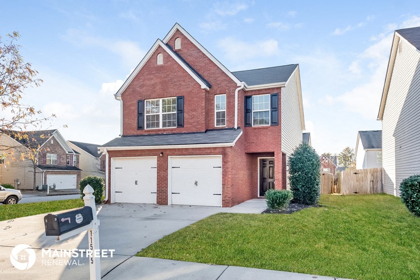 a brick house with white garage doors and a lawn