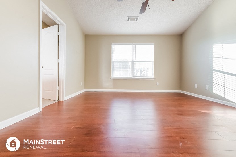 an empty living room with wood floors and a window