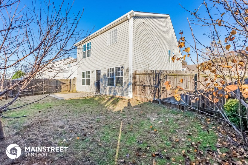 a house with a yard and a fence in front of it
