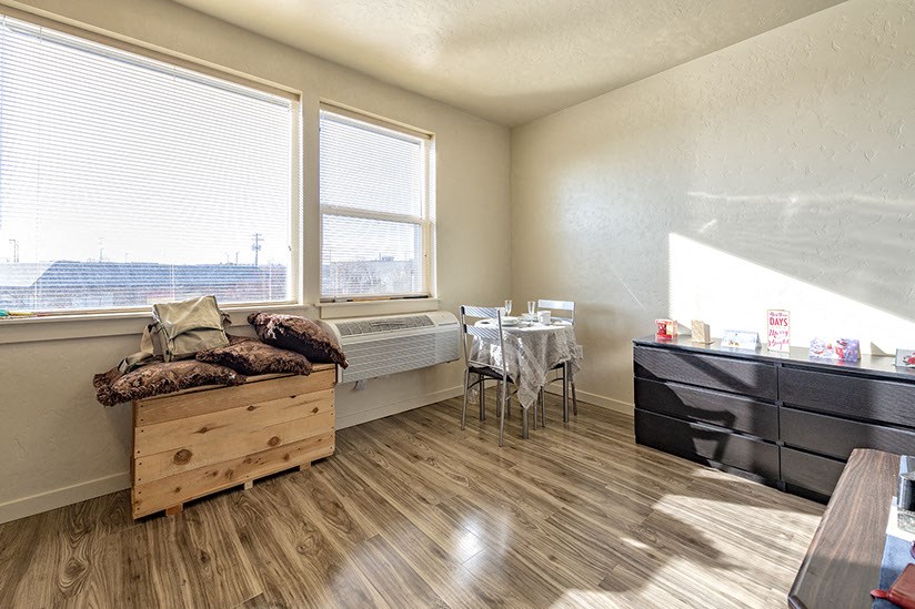 a living room with a bed and a table and two windows