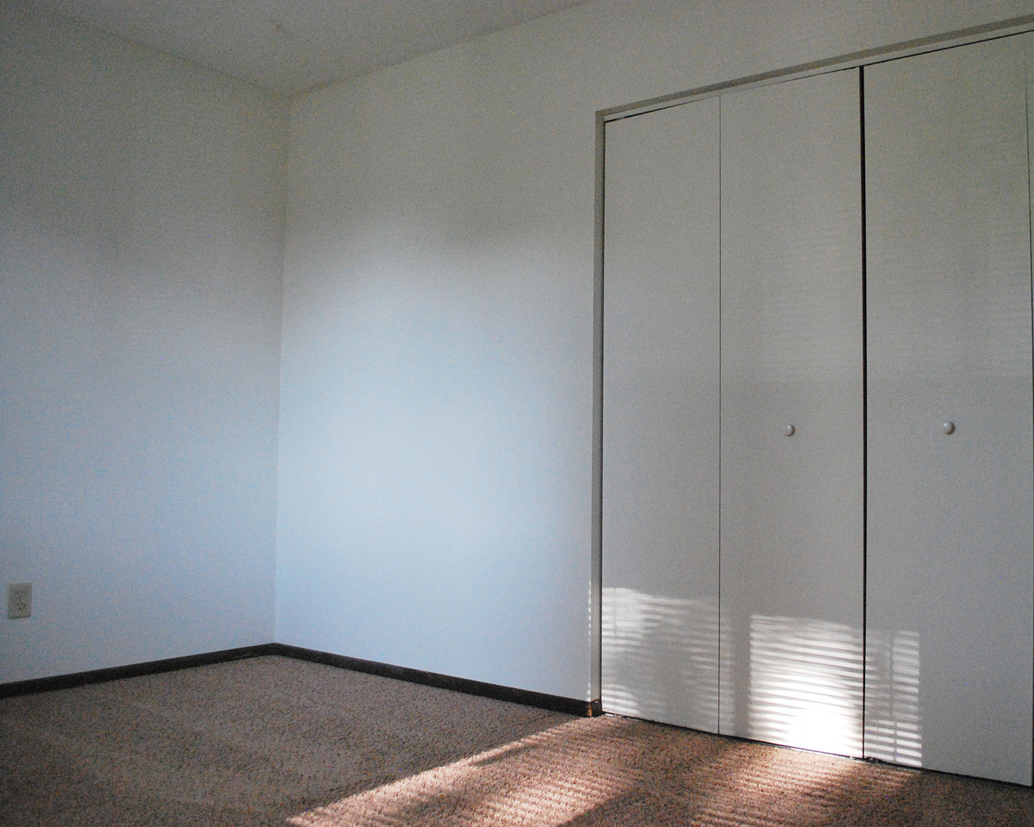 an empty room with white walls and closet doors