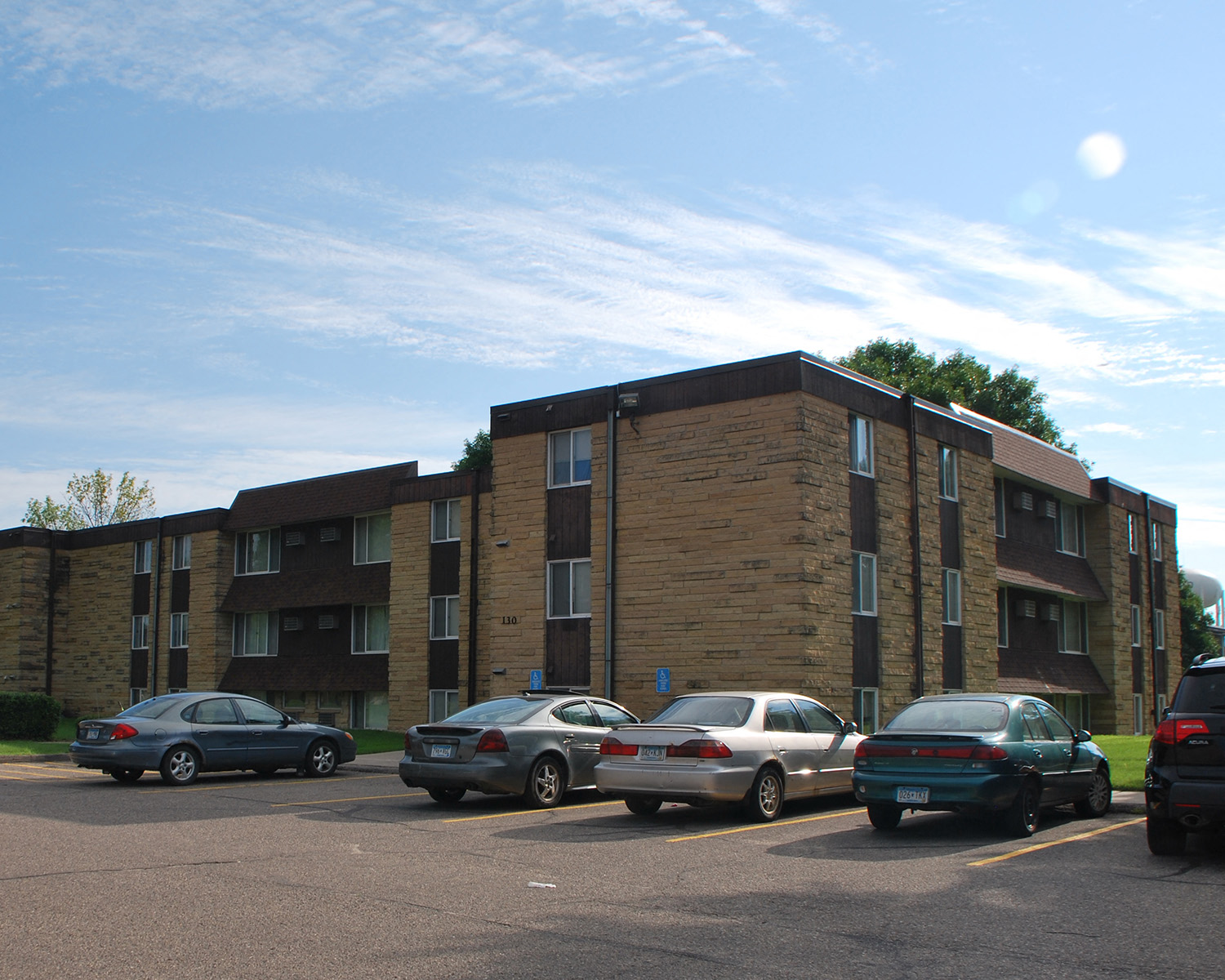 an apartment building with cars parked in a parking lot