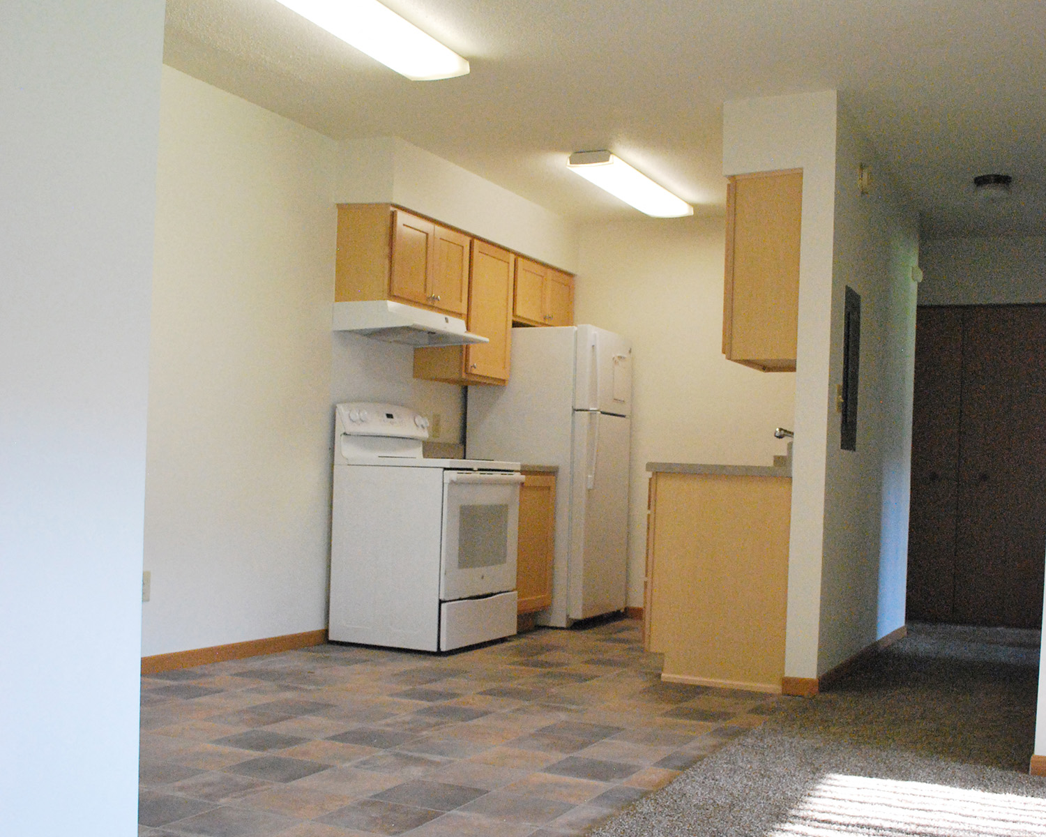 an empty kitchen with a refrigerator and a washer and dryer