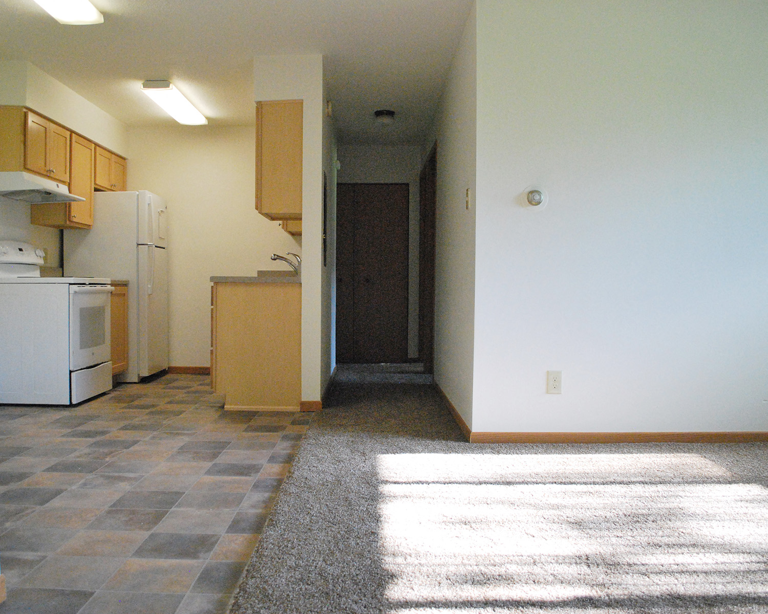 an empty kitchen with white appliances and wood cabinets