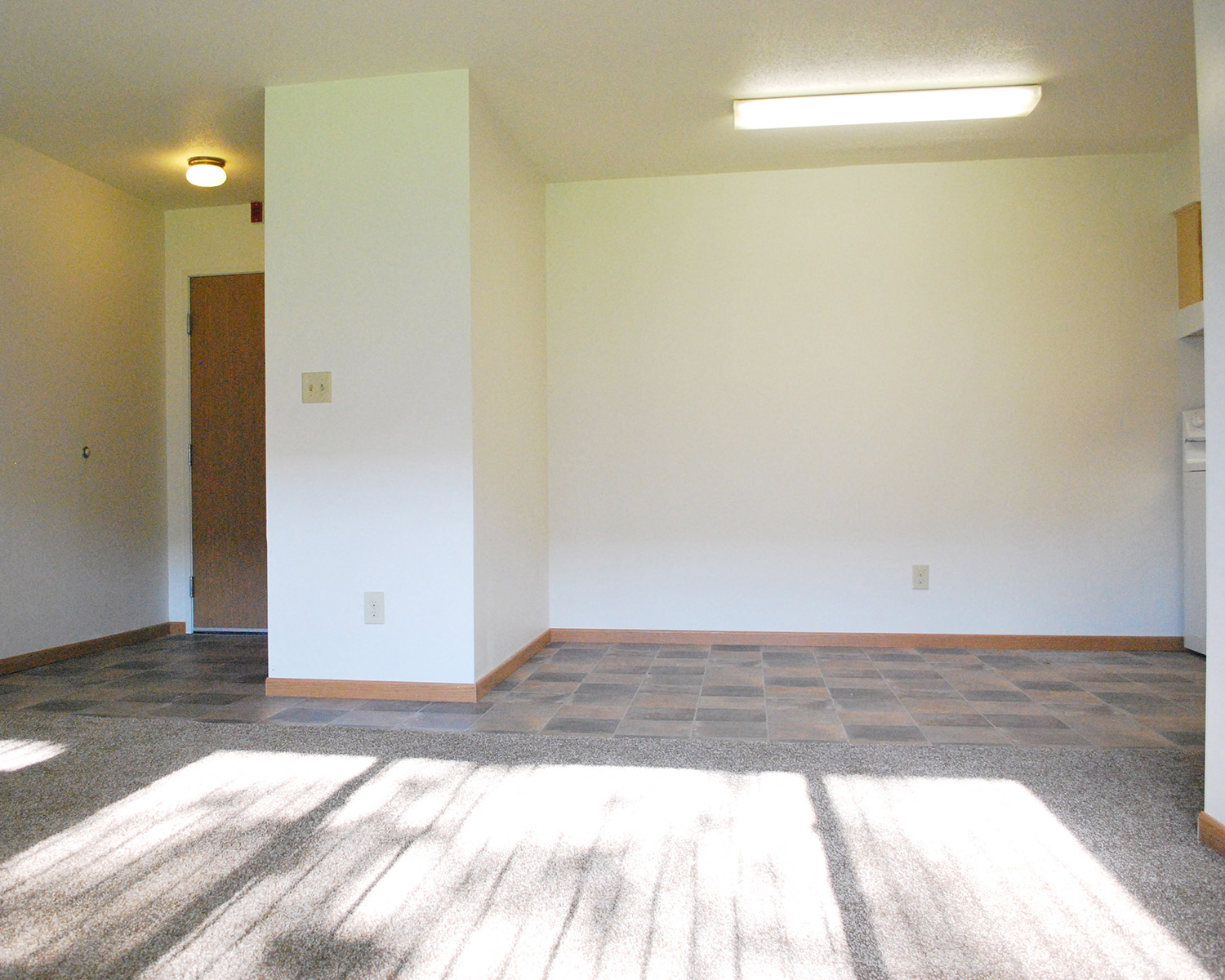 an empty living room with white walls and a tile floor