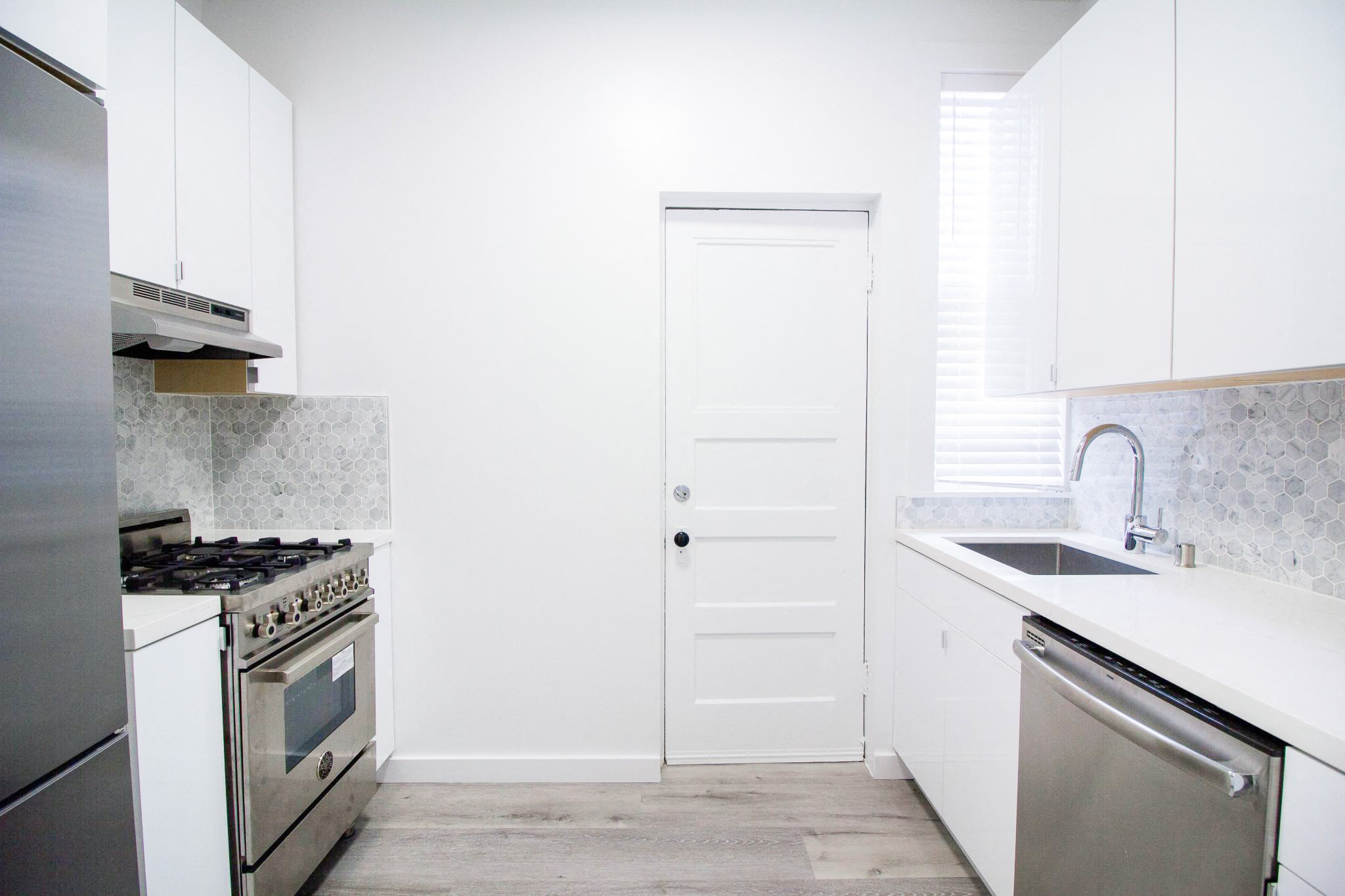 a white kitchen with stainless steel appliances and white cabinets