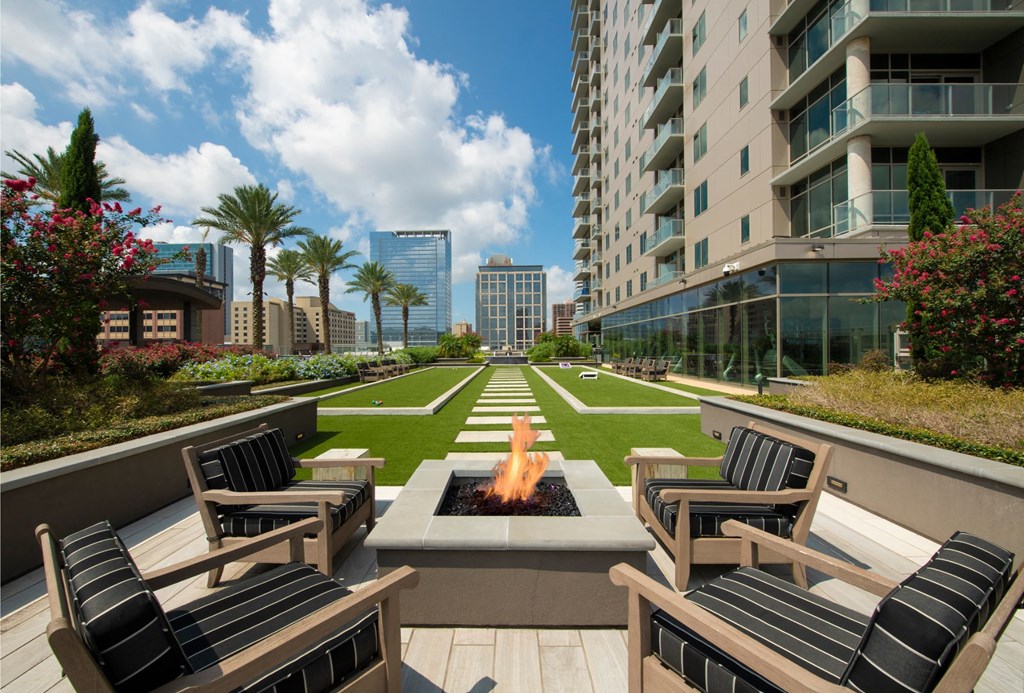 an outdoor lounge area with a fire pit in front of an apartment building