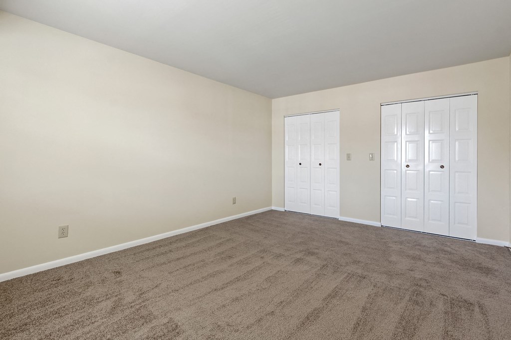 an empty living room with carpet and white doors