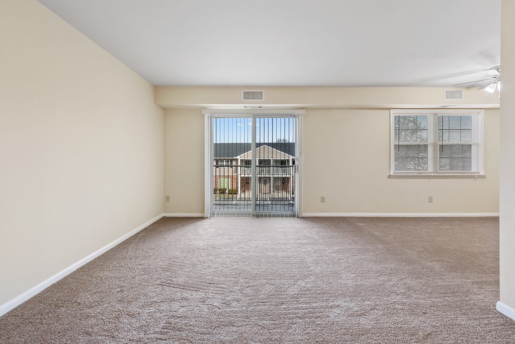 an empty living room with a door to a balcony