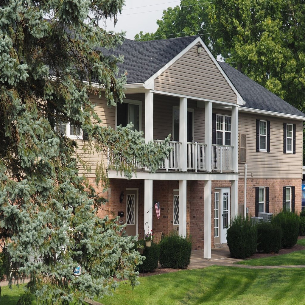 a house with a balcony and a tree in front of it