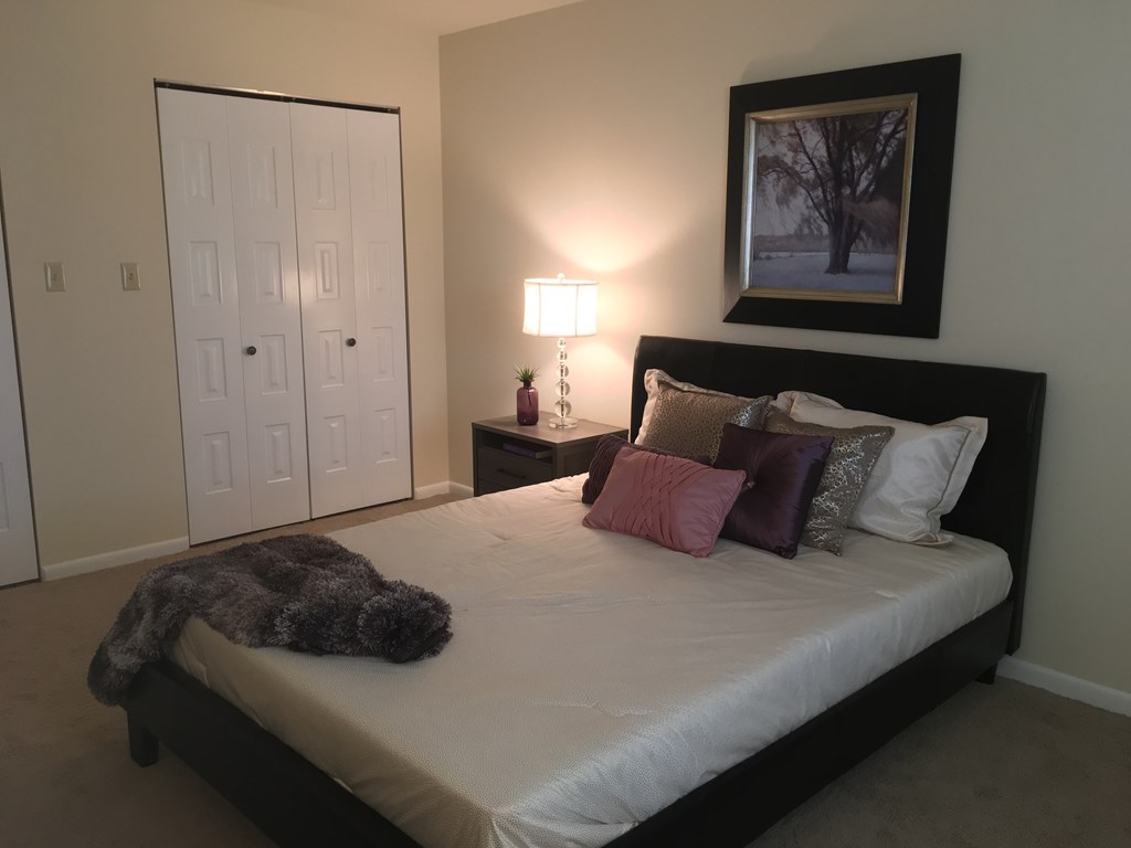 a bedroom with a large bed with pillows and a stuffed animal