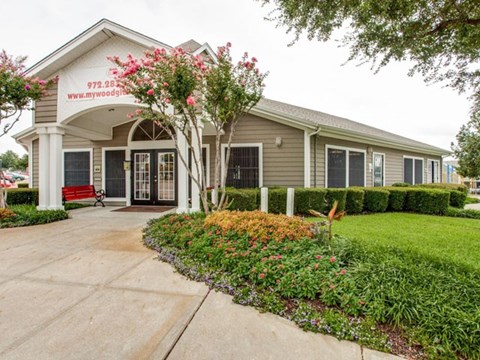 the front of a building with a walkway and grass and flowers