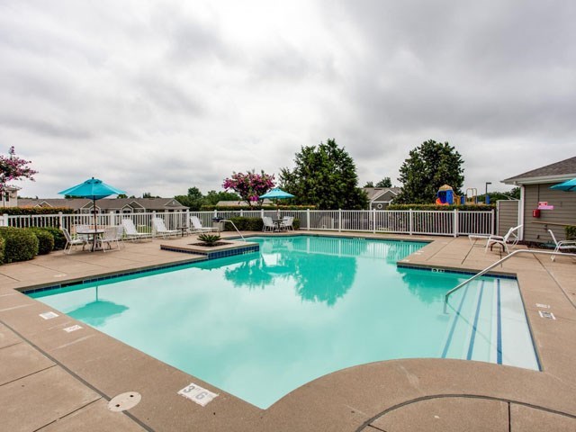 a swimming pool with chairs and umbrellas on a cloudy day